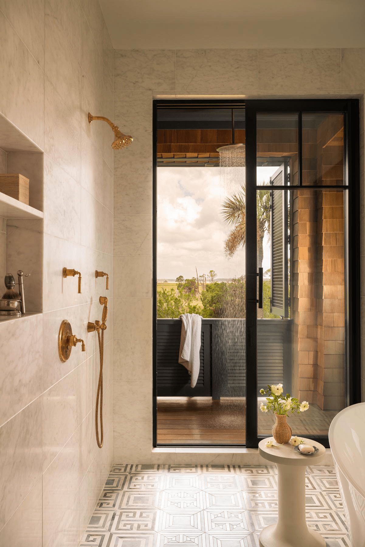 Luxury bathroom with marble tile, brass fixtures, and balcony views
