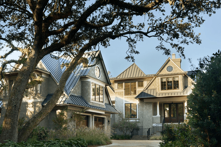 Luxury custom residence exterior with shingle siding and mature oak trees