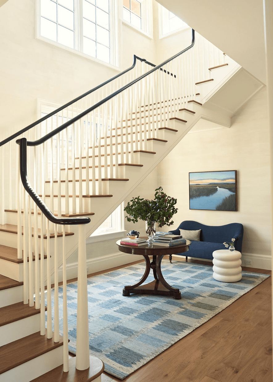 Custom foyer with curved staircase, wood treads, and refined seating area