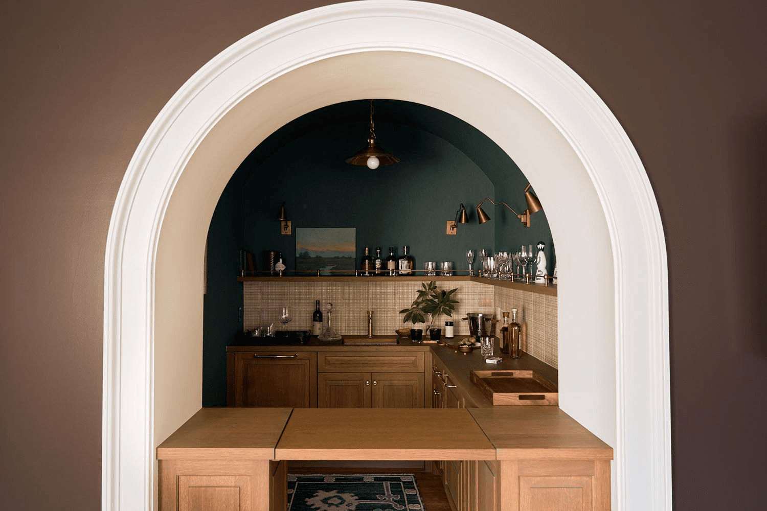 Custom wet bar with arched entry, wood cabinetry, and refined brass details